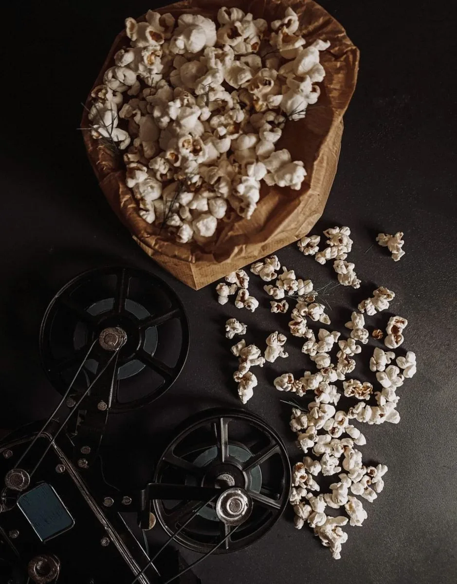 紙袋のポップコーンと、古い映写機のフィルムリール